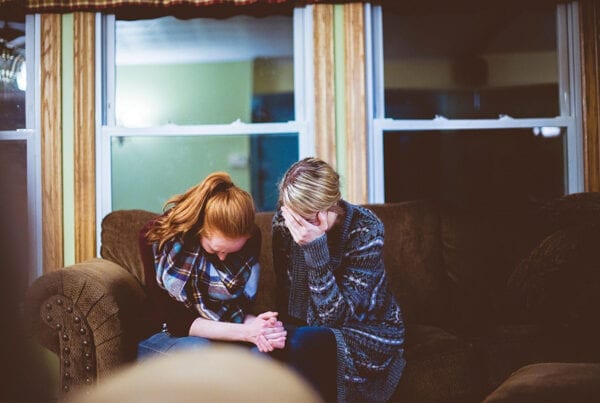 Mother and daughter sitting on sofa in a room, looking worried