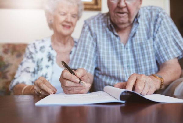 Elderly Caucasian man and woman sitting at home and signing some paperwork.