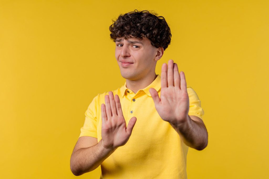 Man in yellow shirt with hands out refusing